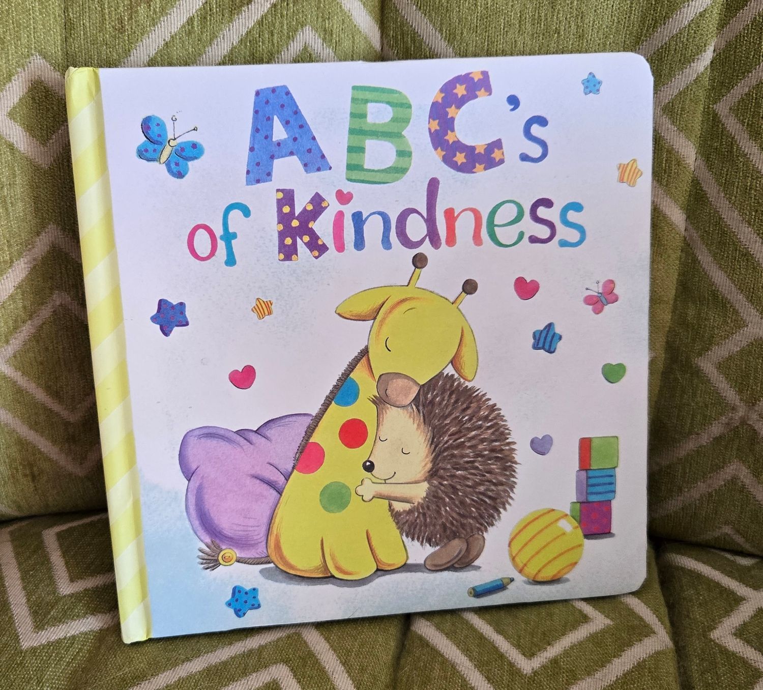 A children's board book titled 'ABC's of Kindness' featuring cute cartoon illustrations of a hedgehog and bunny with hearts and stars.