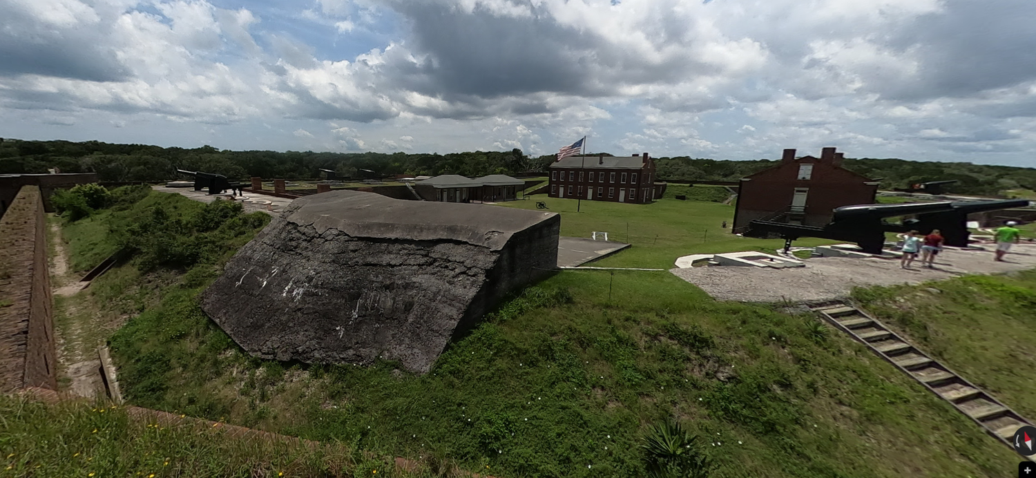 Panoramic view of historic Fort Clinch fortification with brick walls and cannon mounts under cloudy skies.