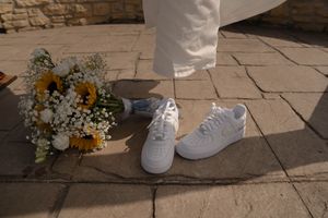 White sneakers and sunflower bouquet arrangement on stone patio during wedding.