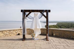 Scenic wedding ceremony setup with wooden pergola overlooking natural landscape.