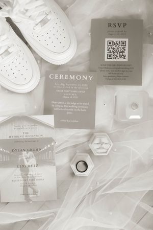 Flat lay of elegant wedding stationery featuring RSVP cards and ceremony details in soft gray tones.