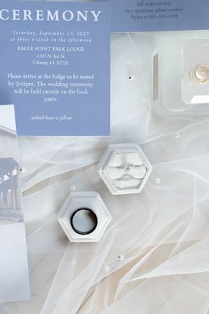 Wedding ceremony details card with text overlay on ethereal white fabric background.