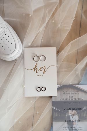 Wedding stationery collection featuring vow books and ring details on delicate tulle fabric.