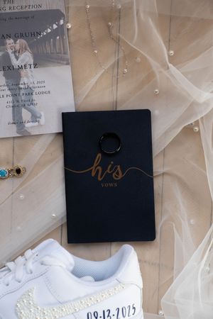 Wedding accessories including customized sneakers and vow books in navy and gold color scheme.