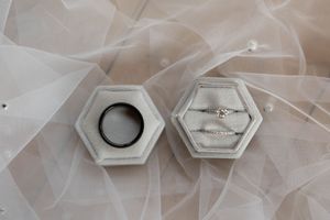 Wedding ring display with hexagonal holders on soft white tulle background.