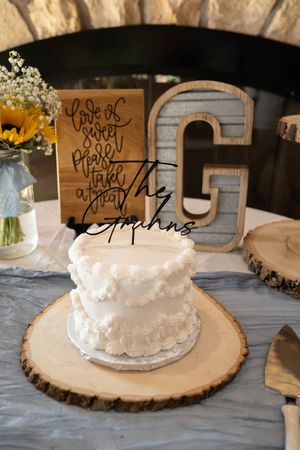 Rustic wedding cake display with wooden slices as stands and handwritten signs.
