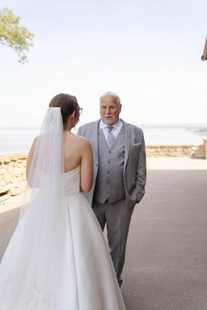 Tender moment between bride and father during wedding first look on outdoor terrace.
