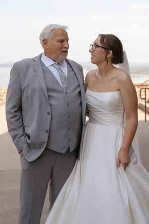 Candid wedding portrait of bride and father sharing joyful moment outdoors.
