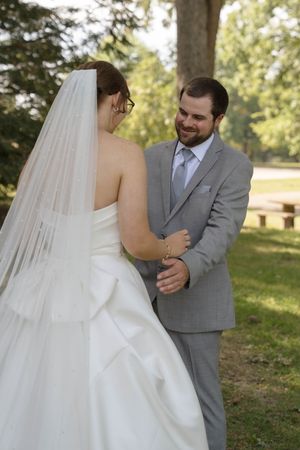 Sweet candid moment between newlyweds sharing smiles during their outdoor wedding.