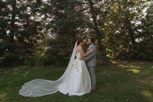 Romantic wedding portrait with flowing veil against a backdrop of evergreen trees.