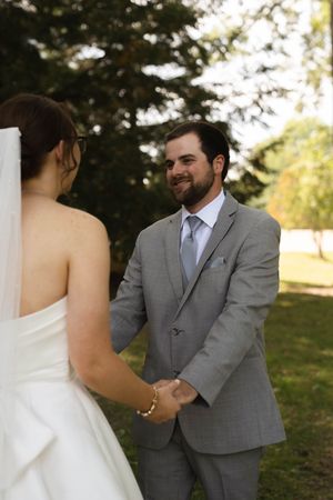 Intimate outdoor wedding moment captured between couple holding hands and exchanging glances.