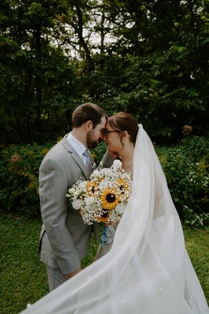 Intimate wedding portrait with sunflower bouquet as couple shares a tender moment.