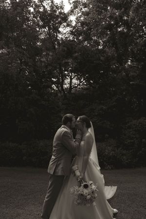 Black and white wedding photo showing an intimate moment between newlyweds in a garden setting.