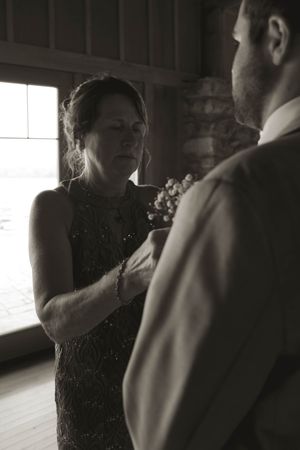 Black and white indoor wedding preparation scene with dramatic window lighting.