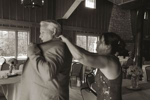 Black and white candid moment of wedding preparations in a rustic indoor setting.
