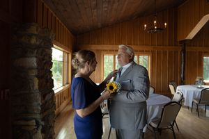 Wedding party members greeting each other in a rustic wooden venue with natural lighting.
