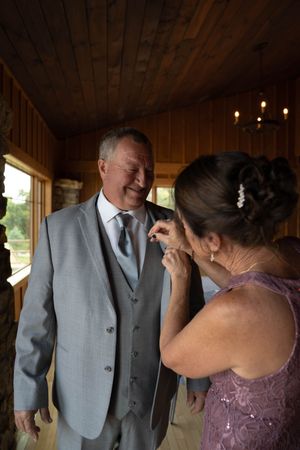 Emotional first look between wedding party members in a rustic indoor setting with wooden walls.