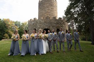 Wedding party members lined up for photos against a stone castle backdrop.