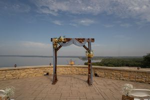 Outdoor wedding ceremony setup with stone wall backdrop and blue sky.