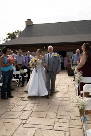 Wedding ceremony setup with white chairs and stone patio.