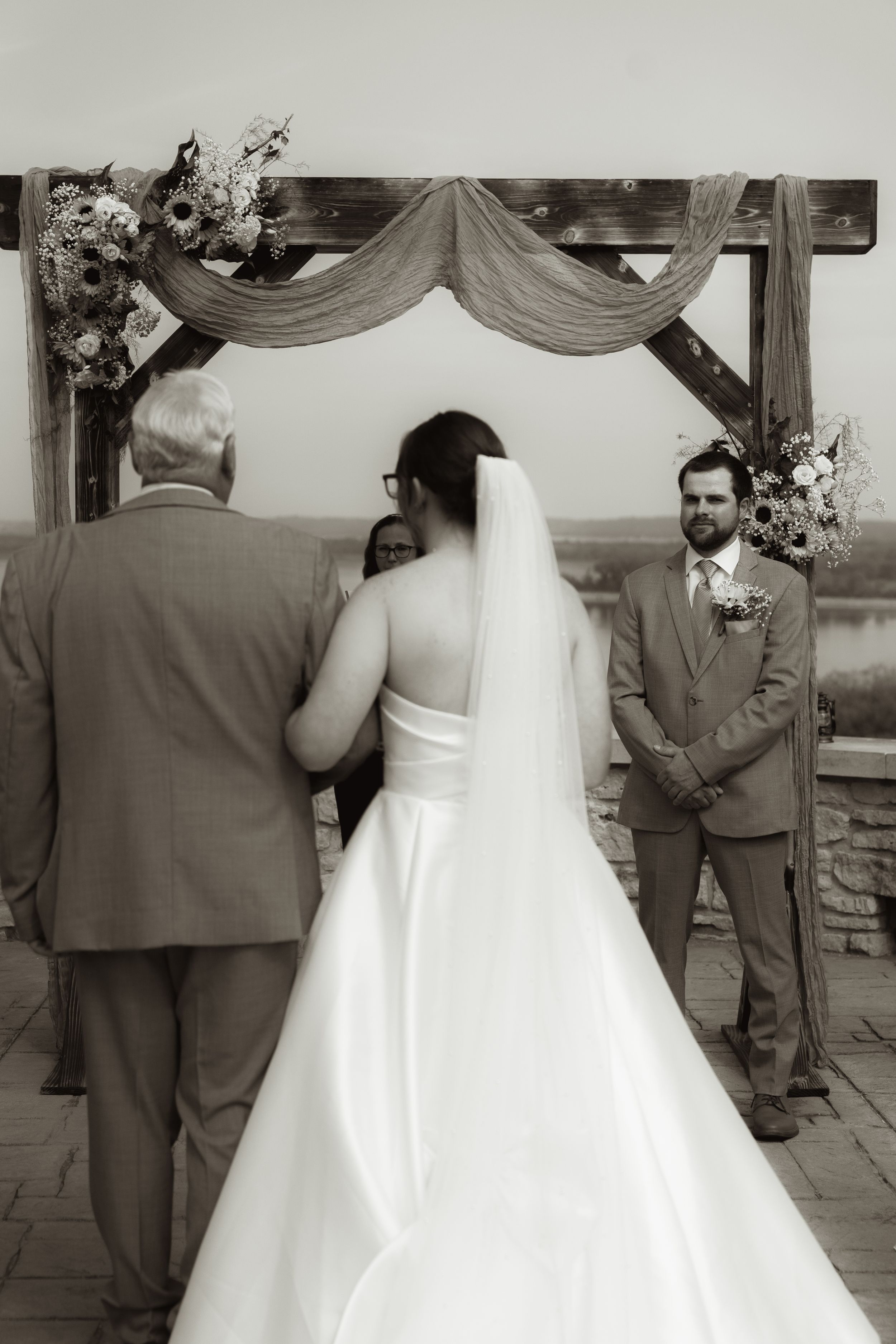 Wedding ceremony at scenic overlook with wooden arch and draped fabric decor.