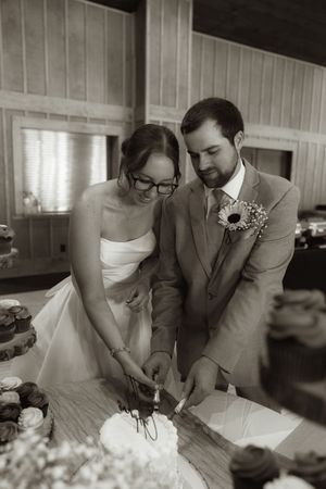 Black and white photo of newlyweds signing marriage documents at reception.