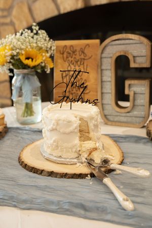 Rustic wedding cake display with mason jars and wooden decor on white tablecloth.