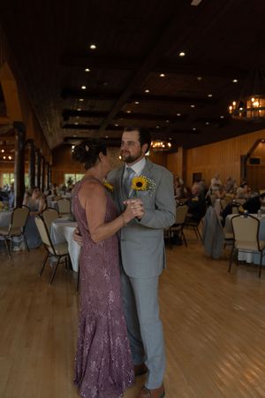 Dancing couple in purple dress and gray suit during wedding reception.