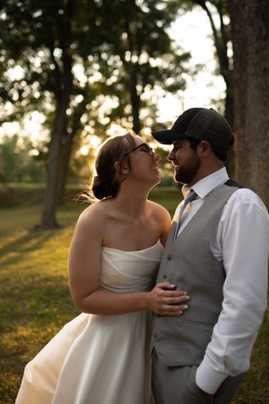Romantic sunset moment between couple in wedding attire among trees.