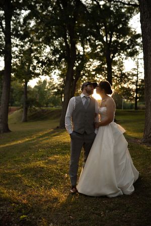Couple shares intimate moments during golden hour wedding photoshoot in wooded setting.