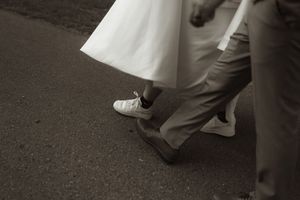 Wedding dress and formal shoes detail shot on dark background.