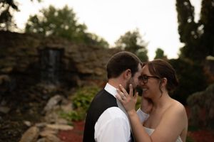 Romantic wedding portrait against stone wall with waterfall feature at dusk.