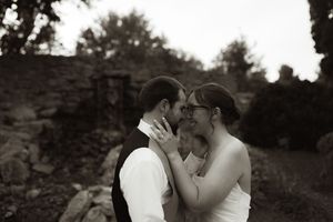 Black and white wedding portrait showing tender embrace against stone backdrop.