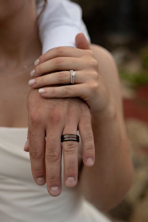 Detail shot of overlapping hands displaying matching wedding bands.