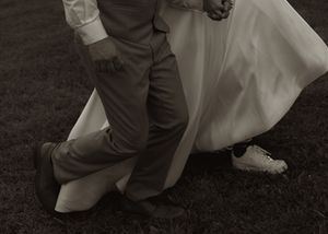 A couple dancing together on grass with flowing white wedding dress creating movement.