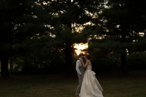 Silhouettes of a wedding couple embracing during golden hour in a park setting.