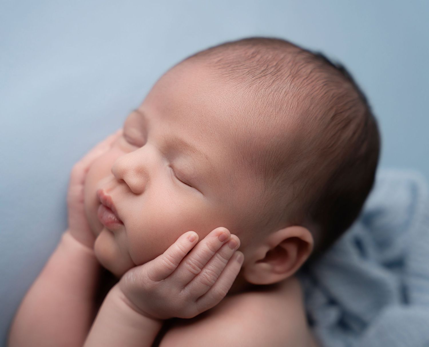 Miami Maternity photographer A sleeping newborn baby lies peacefully on soft blue fabric in a series of artistic close-up portraits.