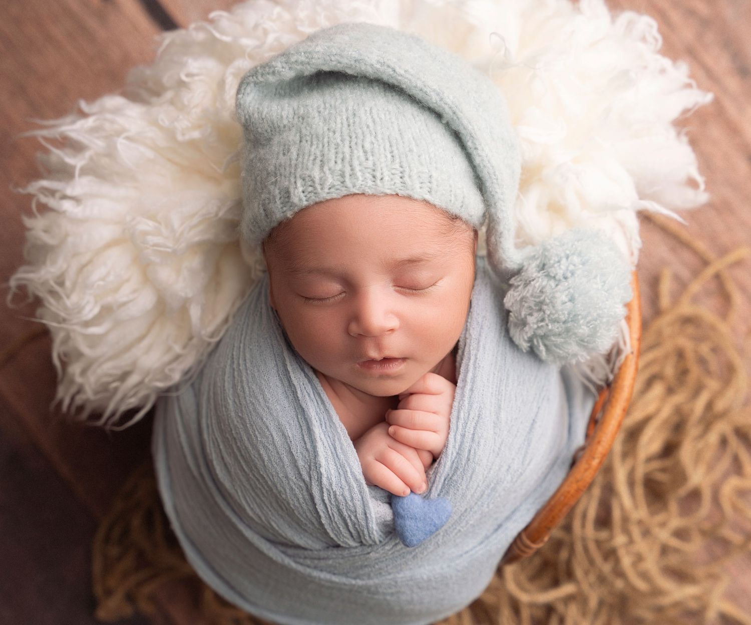 Miami Maternity photographer Newborn baby wrapped in soft gray swaddle with white feather sleeps peacefully during photography session.