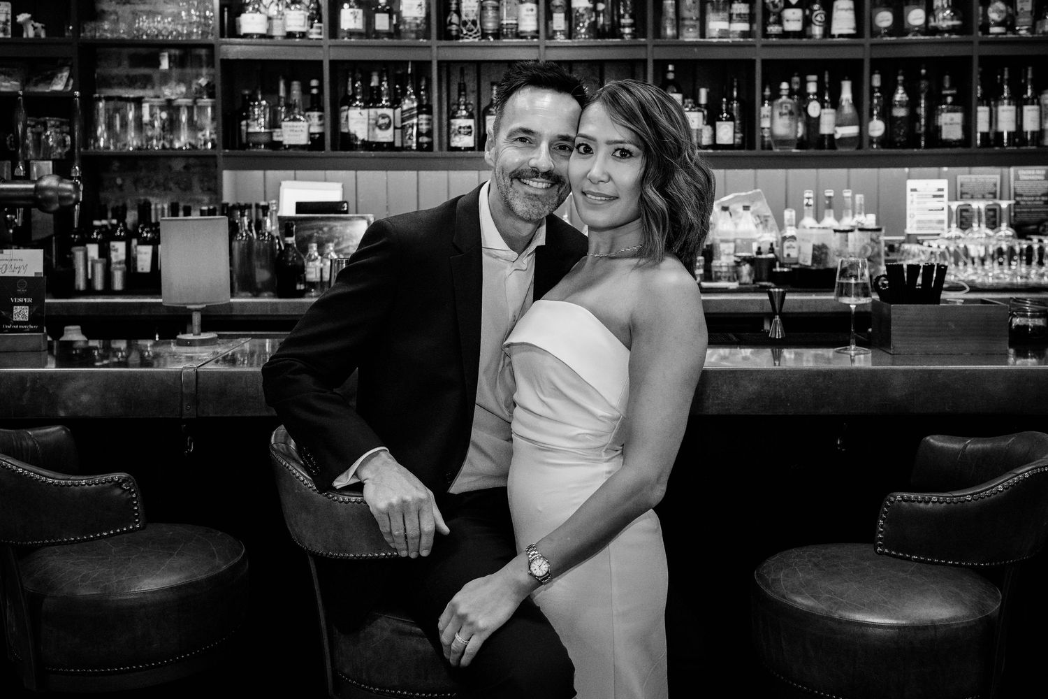 Black and white photos of a couple celebrating at a bar counter during their wedding reception.