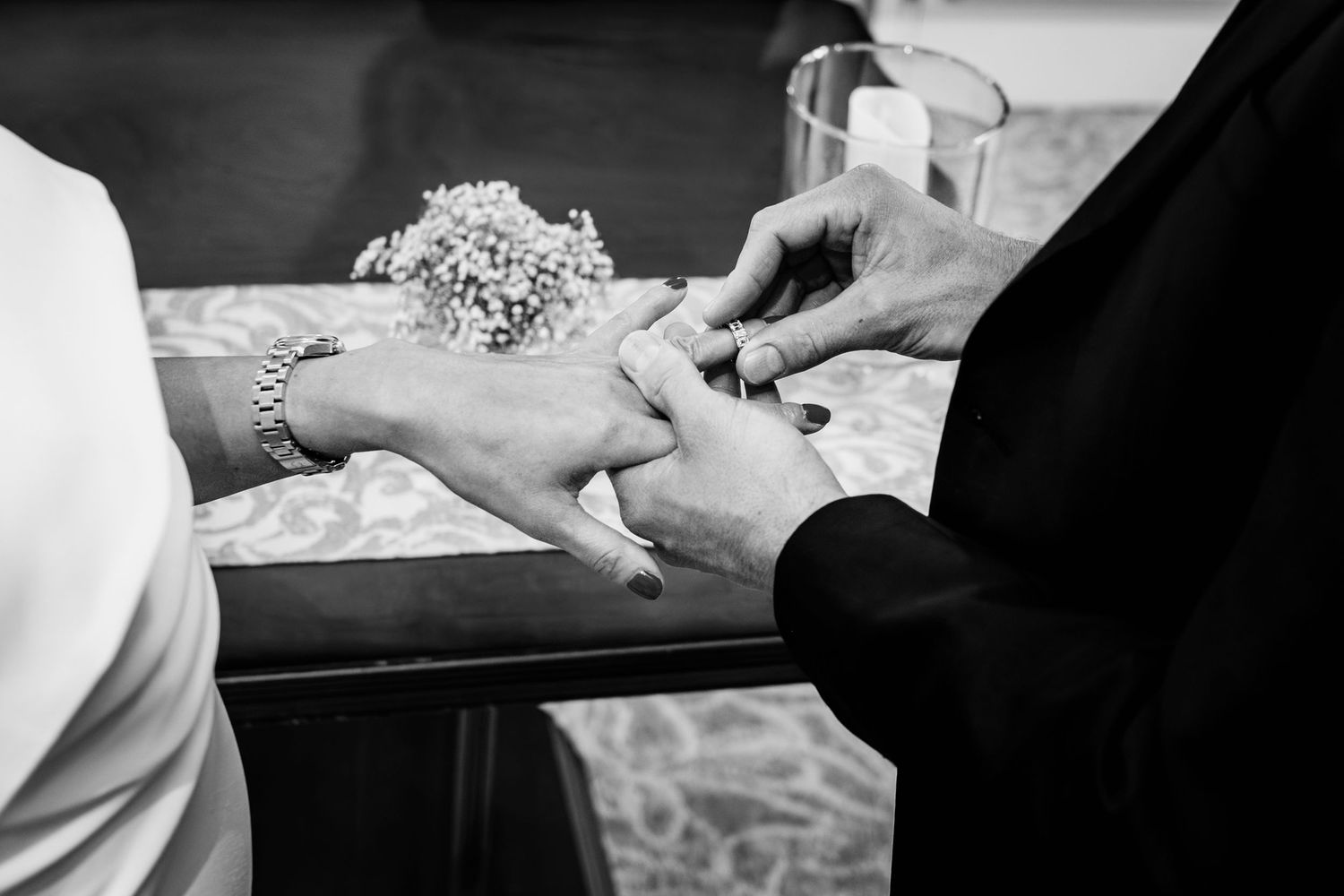 Black and white image showing hands preparing and kneading dough on a floured work surface.