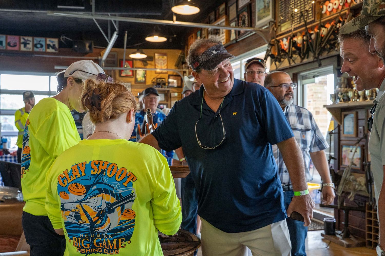 People gather at a lively indoor event wearing bright yellow t-shirts and dark jackets in a casual setting.