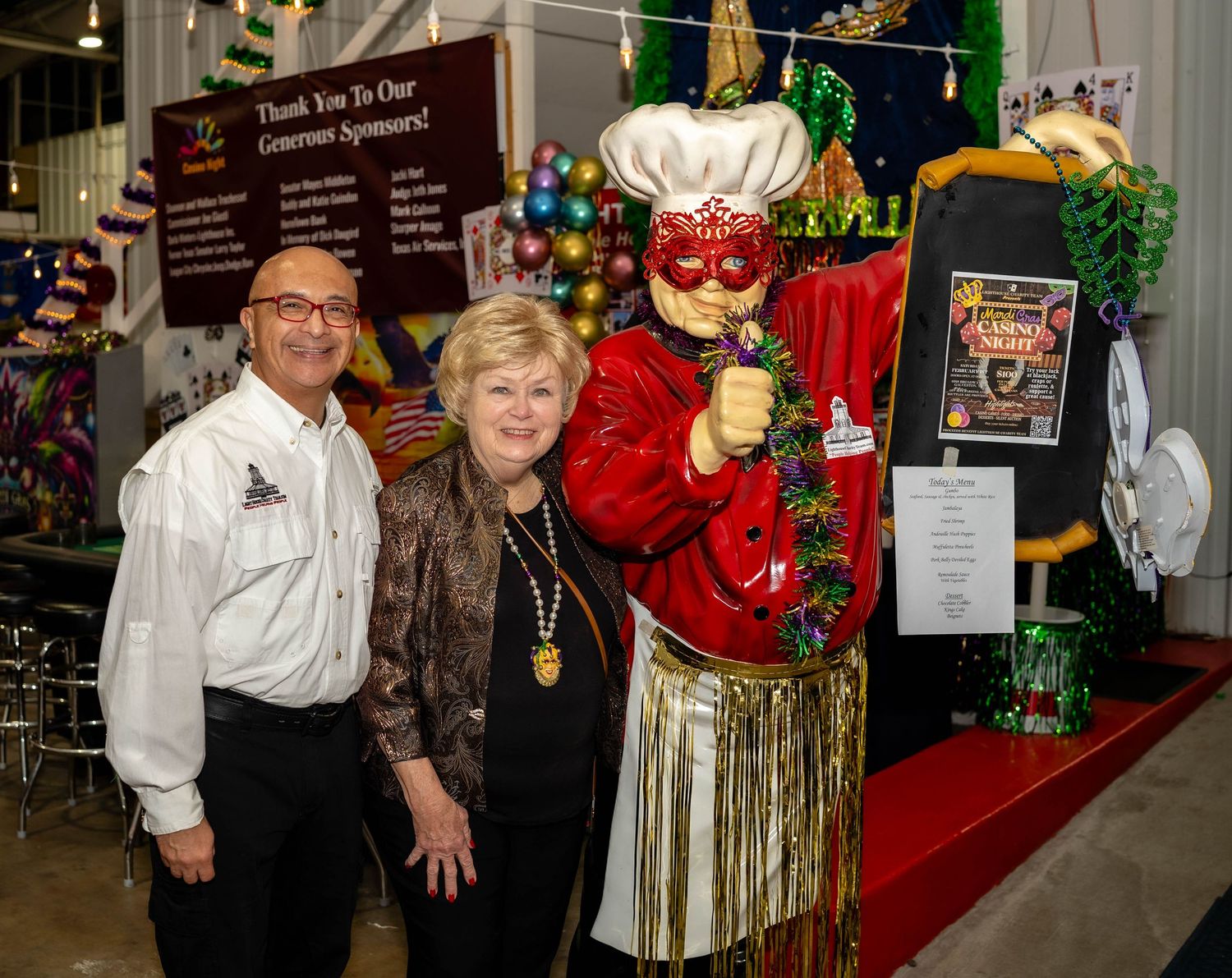 Festive holiday party scene with people in formal attire gathered around decorative Christmas displays and ornaments.