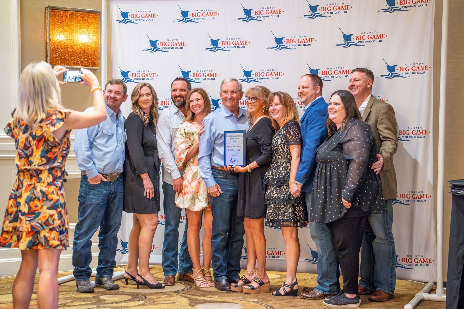 A group of people standing in line against a backdrop wall with corporate logos at a formal event.