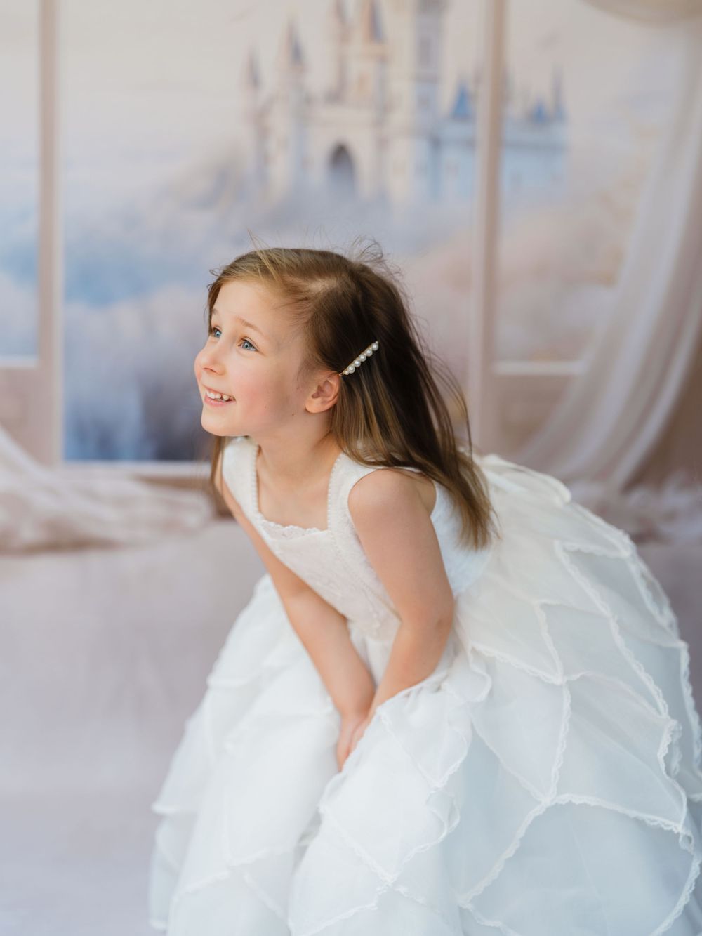 A young ballet dancer in a white tutu dress performs graceful movements in a bright studio setting.