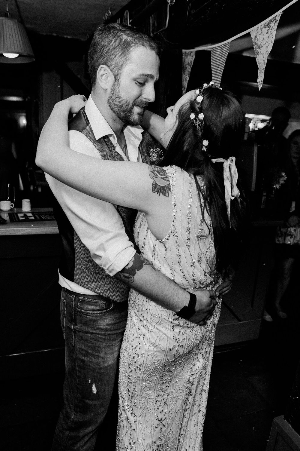 A couple shares an intimate dance moment in a dimly lit venue, with the woman wearing a sparkly dress.