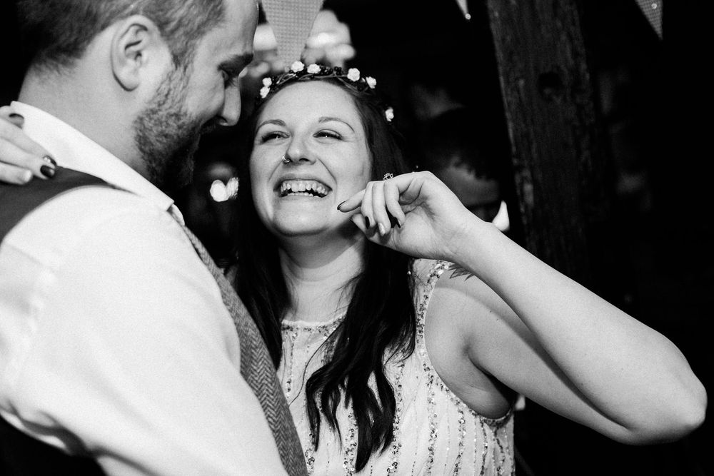 A black and white photo series showing joyful moments of a couple dancing and embracing at a wedding celebration.