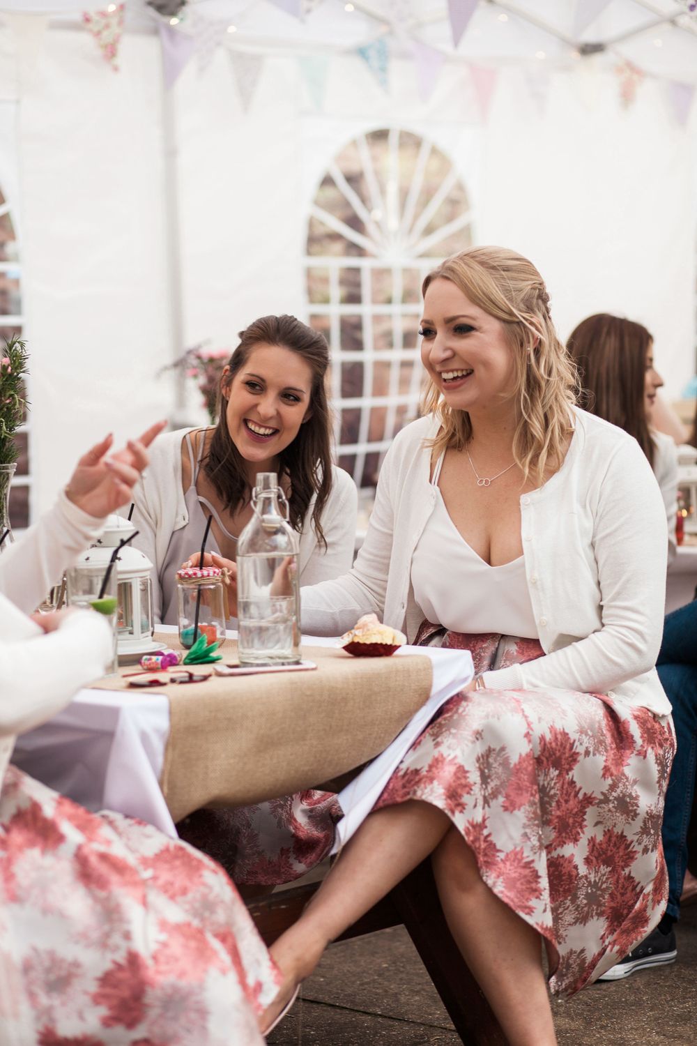 Wedding celebration in a marquee tent with guests seated at tables decorated with burlap linens and bunting.