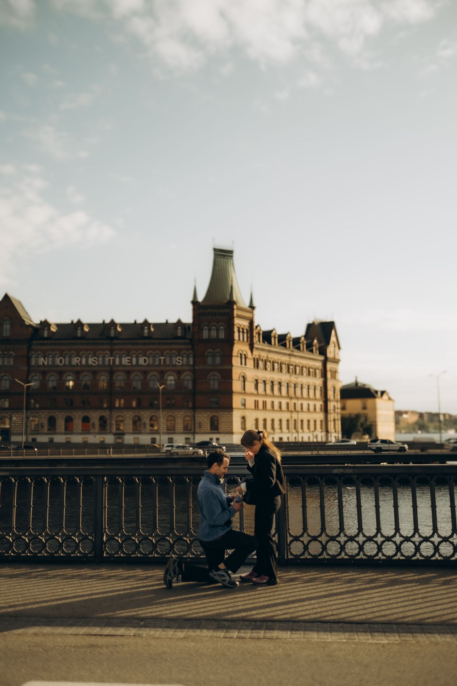 man getting down on one knee to propose to his girlfriend on Vasa bridge while being captured by secret proposal photographer in Stockholm