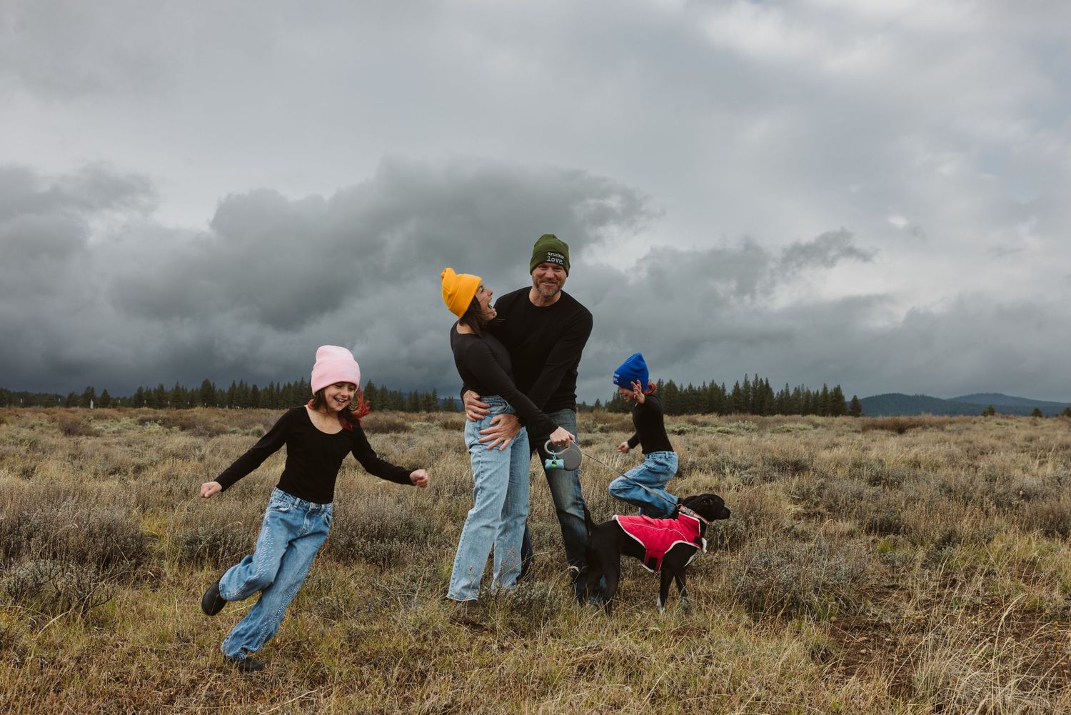 Playful figures dance and jump through a series of candid moments in a grassy field under moody skies.