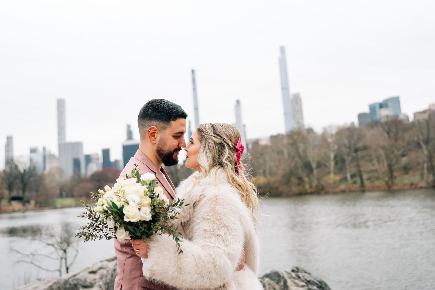 Romantic winter photoshoot in Central Park with NYC skyline and lake in the background.